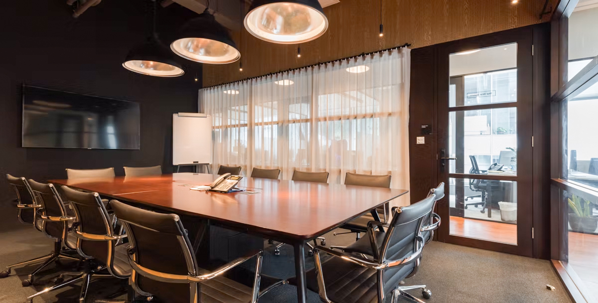 The Hive Causeway Bay — a 12-seat boardroom with a long table, leather chairs, and floor-to-ceiling windows.