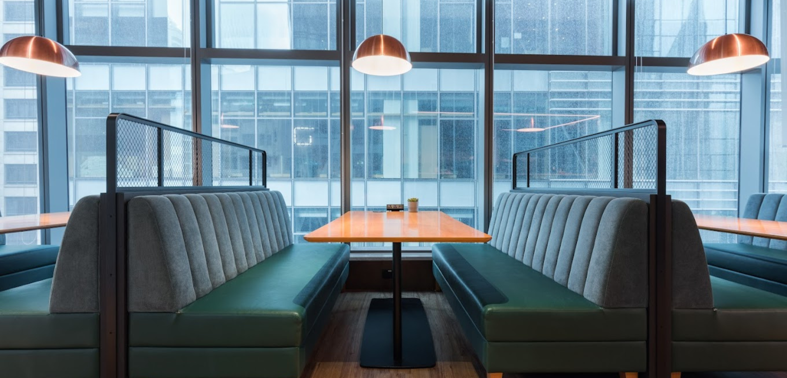 The Hive Causeway Bay — banquette booths in front of floor-to-ceiling glass overlooking the Hong Kong skyline.