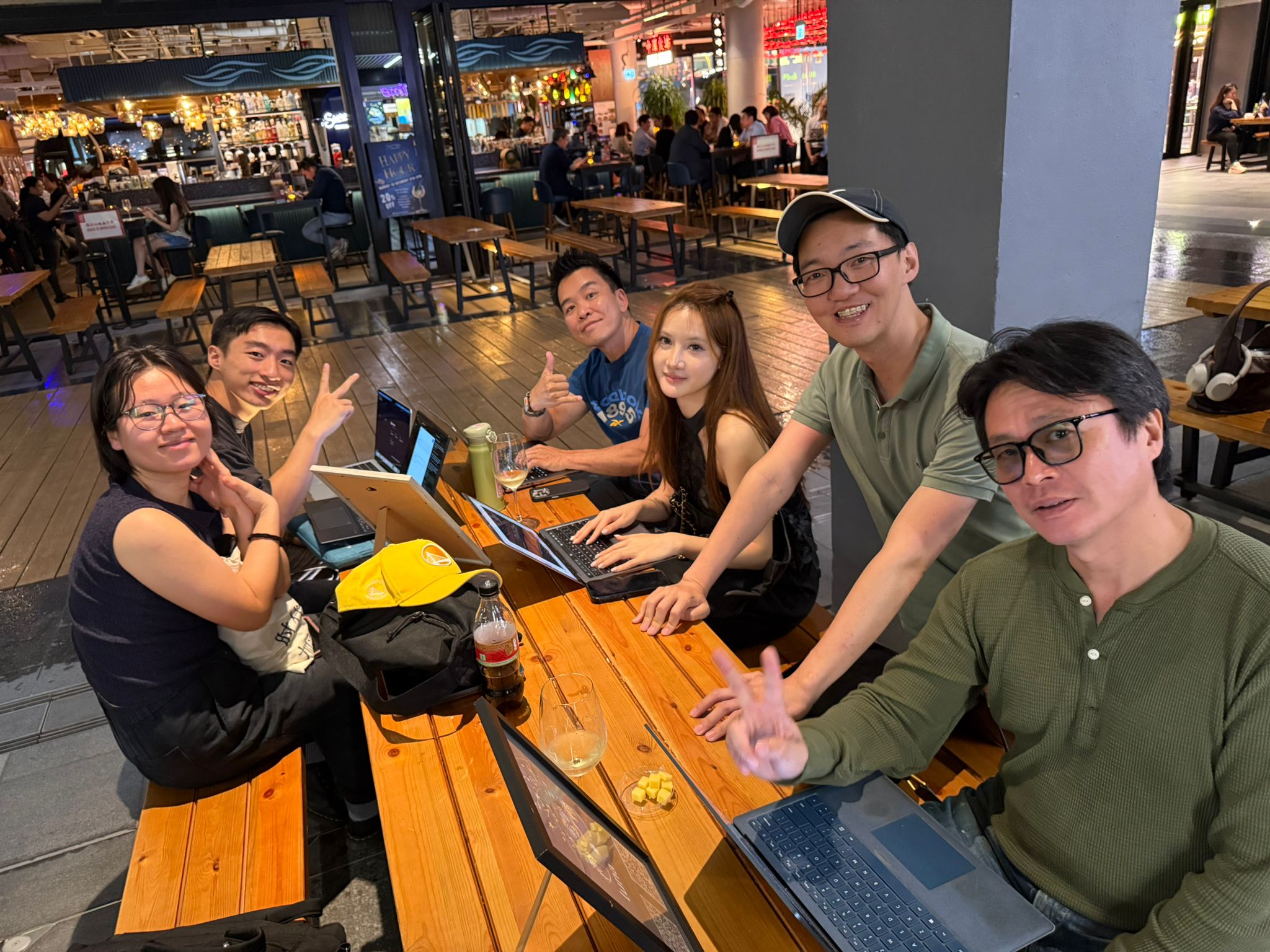 Builders at a table with V-signs, laptops open