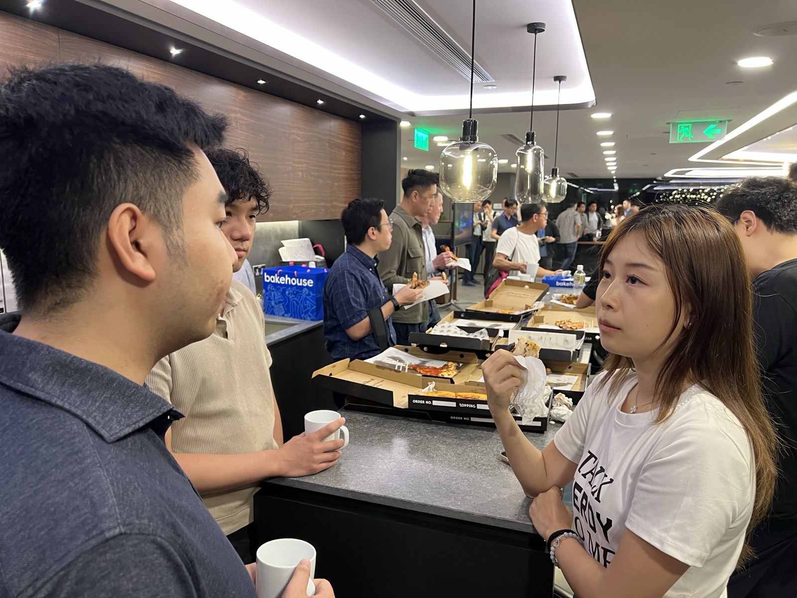 Three attendees in close conversation at the pizza counter