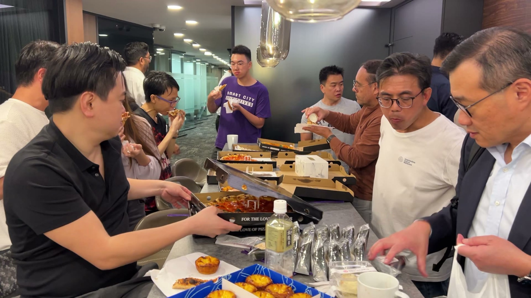 Attendees gathered at the pizza counter, mid-conversation